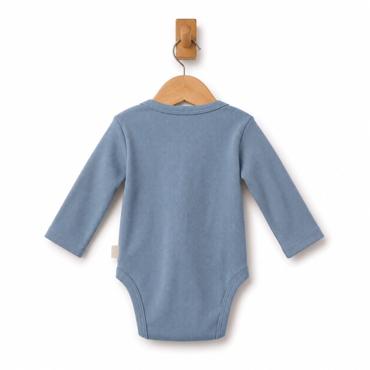 A light blue ribbed long-sleeve baby bodysuit shown from the back, hanging on a wooden hanger from a wall hook against a white background.