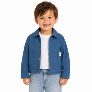 A young boy smiling, wearing a blue shacket over a white t-shirt and light blue jeans, photographed against a solid white background.