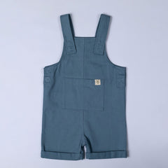 Blue dungaree shorts with a close up of the large front pocket with windmill hem tag