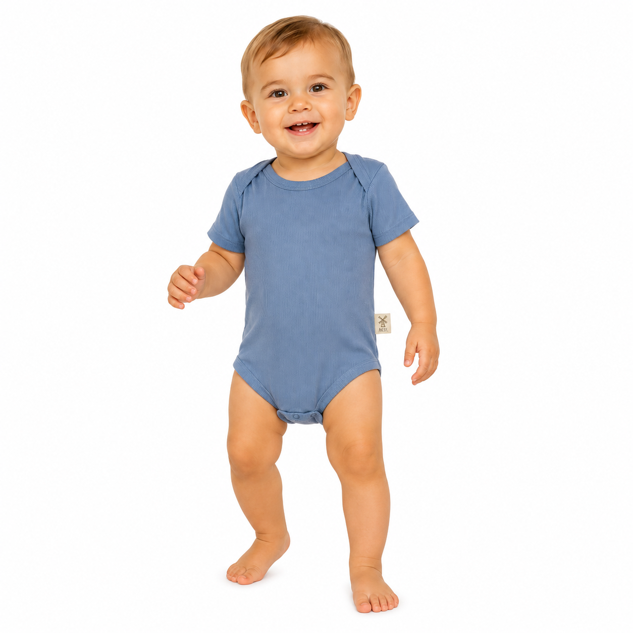 A smiling toddler standing barefoot on a white background, wearing a short-sleeve blue bodysuit with a small beige Aneby windmill tag on the side.