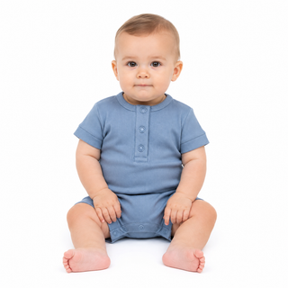 A baby sitting on a white studio background wearing a dusty blue short-sleeve romper with three poppers on the chest.