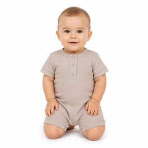 A baby wearing a short-sleeve romper in a light beige colour, kneeling on a white background.