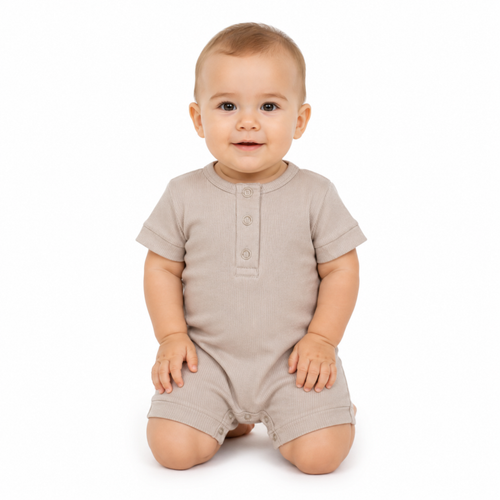 A baby wearing a short-sleeve romper in a light beige colour, kneeling on a white background.