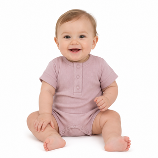 A smiling baby sitting on a white background, wearing a short-sleeve romper in a pink colour.