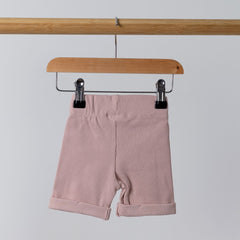 Rear view of pink jersey rib shorts with elasticated waist on wooden hanger