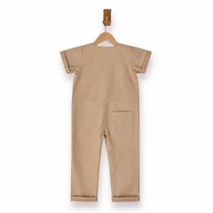 A beige short-sleeve one-piece jumpsuit shown from the back, hanging on a wooden hanger against a plain white background.