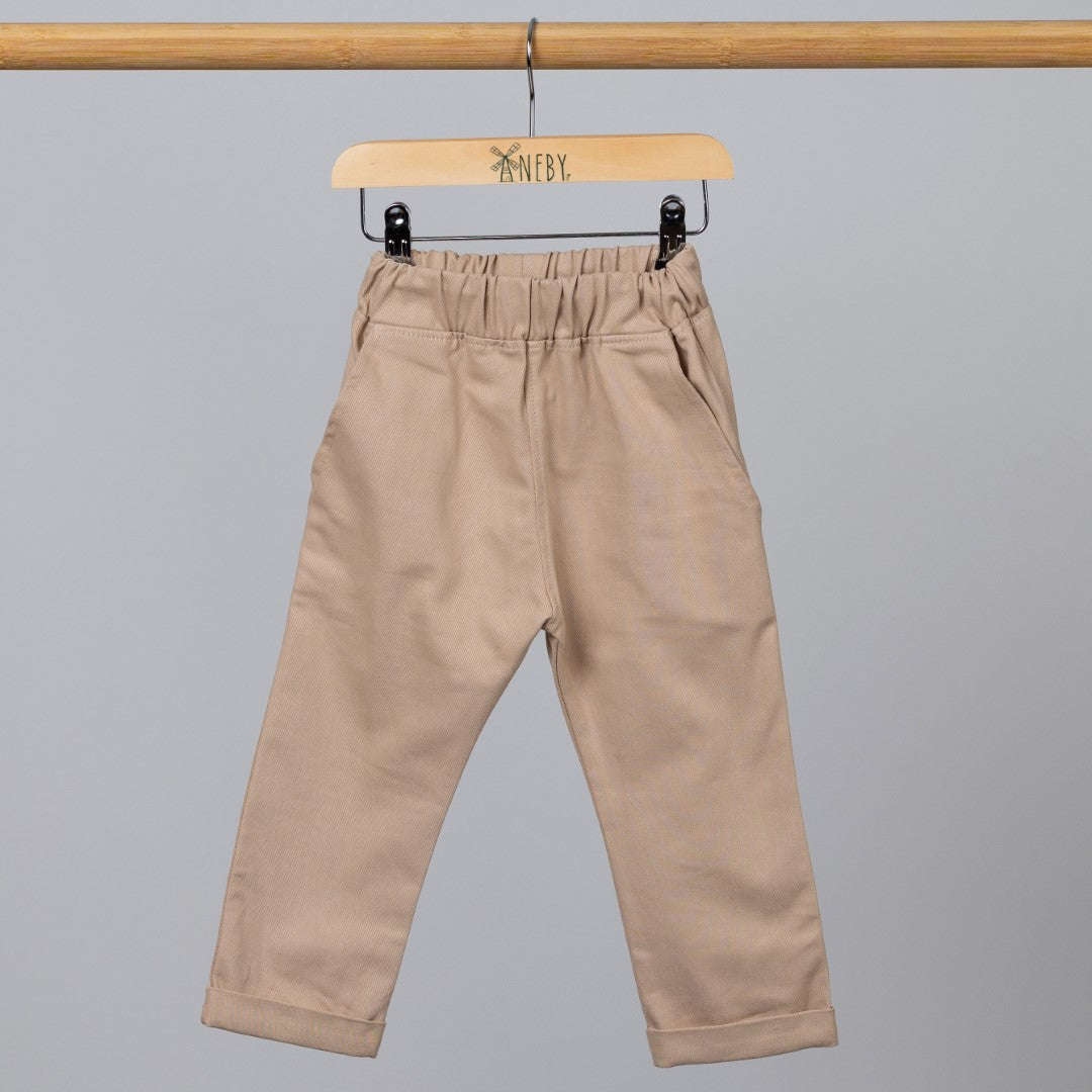 Neutral coloured chinos with pockets and elasticated waist on a wooden clothes hanger