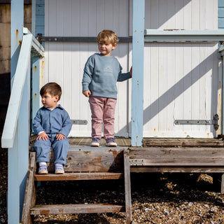 Two Aneby models standing on the decking of a weathered beach hut with rustic looking beams