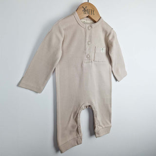 Beige ribbed cotton baby jumpsuit laid flat on a neutral background, showing the front design.