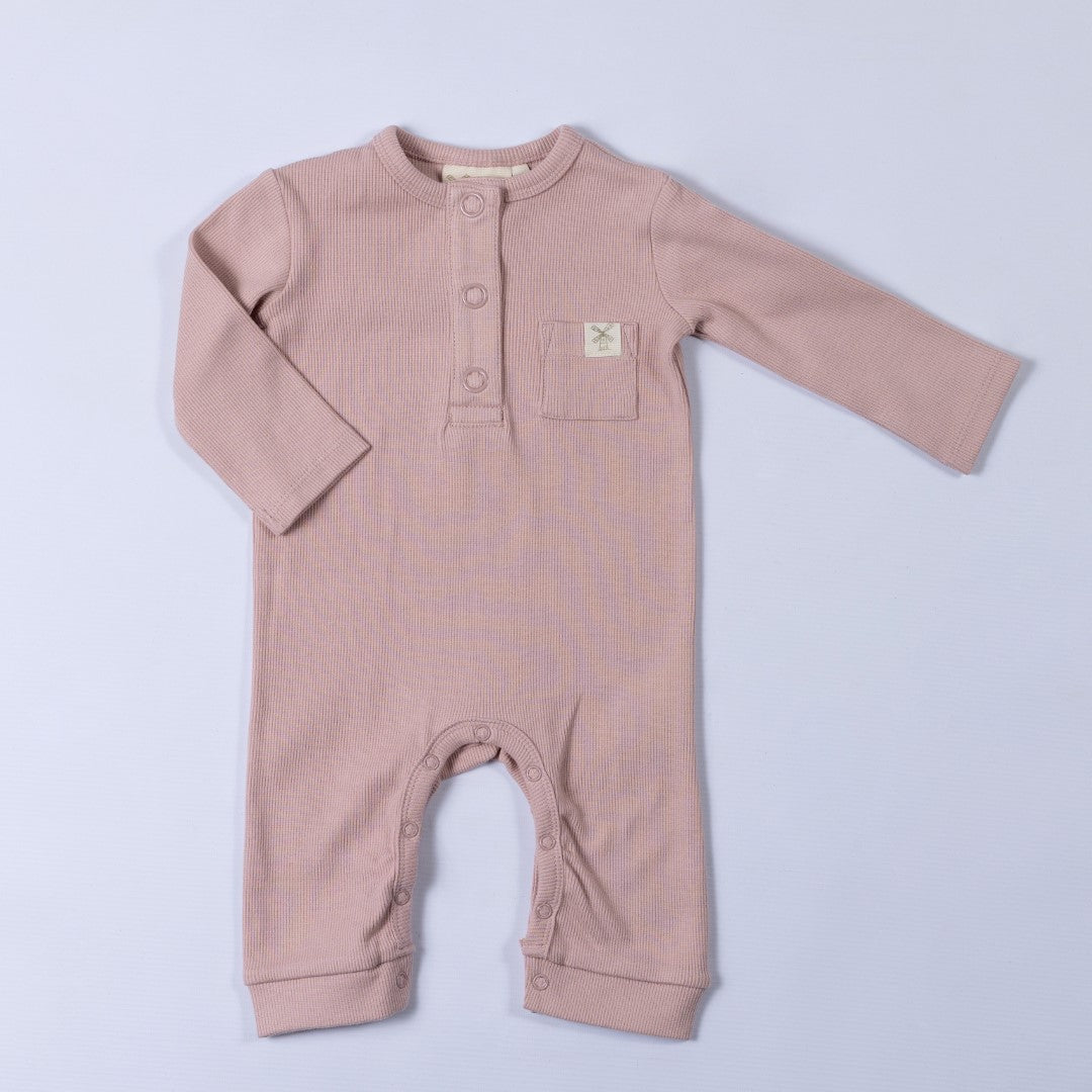 Dusty pink ribbed cotton baby jumpsuit laid flat on a neutral background, showing the front design.