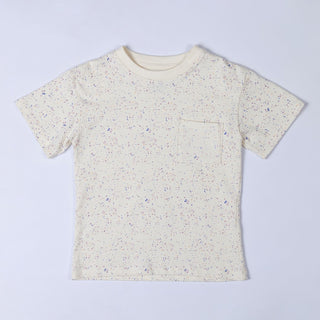 Flat lay of an ecru children's paint splat t-shirt, front view. The t-shirt features a scattered paint splatter pattern in soft pastel and earthy tones, adding a creative and playful look.