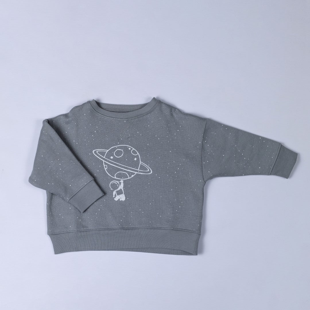 Close-up flat lay of the children's spaceman sweatshirt in grey, showing subtle star details across the fabric. Displayed against a neutral background.