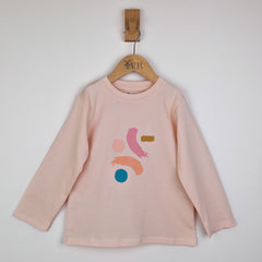 Front flat lay of a girls dusty pink long sleeve t-shirt with a round neckline and subtle stitched hem, displayed against a neutral surface to showcase the colour and shape.
