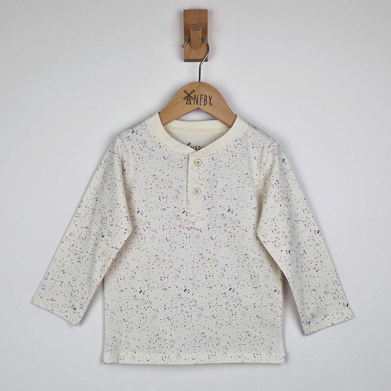 Flat lay of a kids long sleeve ecru t-shirt showing close-up detail of the speckled print and relaxed fit, neutral background. 