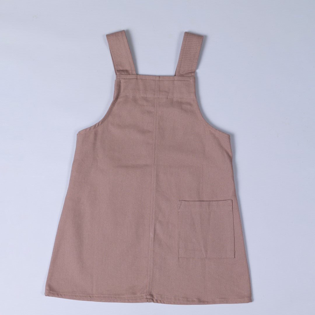 Flat lay of the back of a dusty pink organic cotton dungaree dress, with trendy straps and detailed stitching