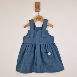 Flat lay of a slate blue girls’ pleated dress with straps, carefully positioned to showcase the front design and smooth pleated skirt.