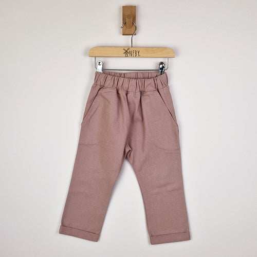 Front view of dusty pink chino-style elasticated trousers on a wooden hanger.