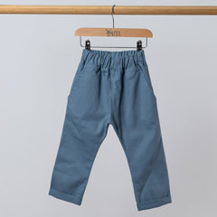 Front view of slate blue chino-style elasticated trousers hanging from a wooden clothing frame.