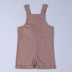 Flat lay of dusty pink kids' cotton dungaree shorts, back view. Showcasing a classic dungaree strap design with a rear pocket for added functionality.