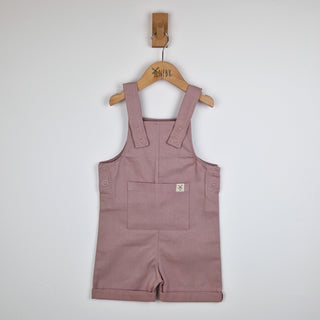 Flat lay of dusty pink kids' cotton dungaree shorts, front view. A soft pastel colour, designed with breathable organic cotton for comfortable everyday wear.