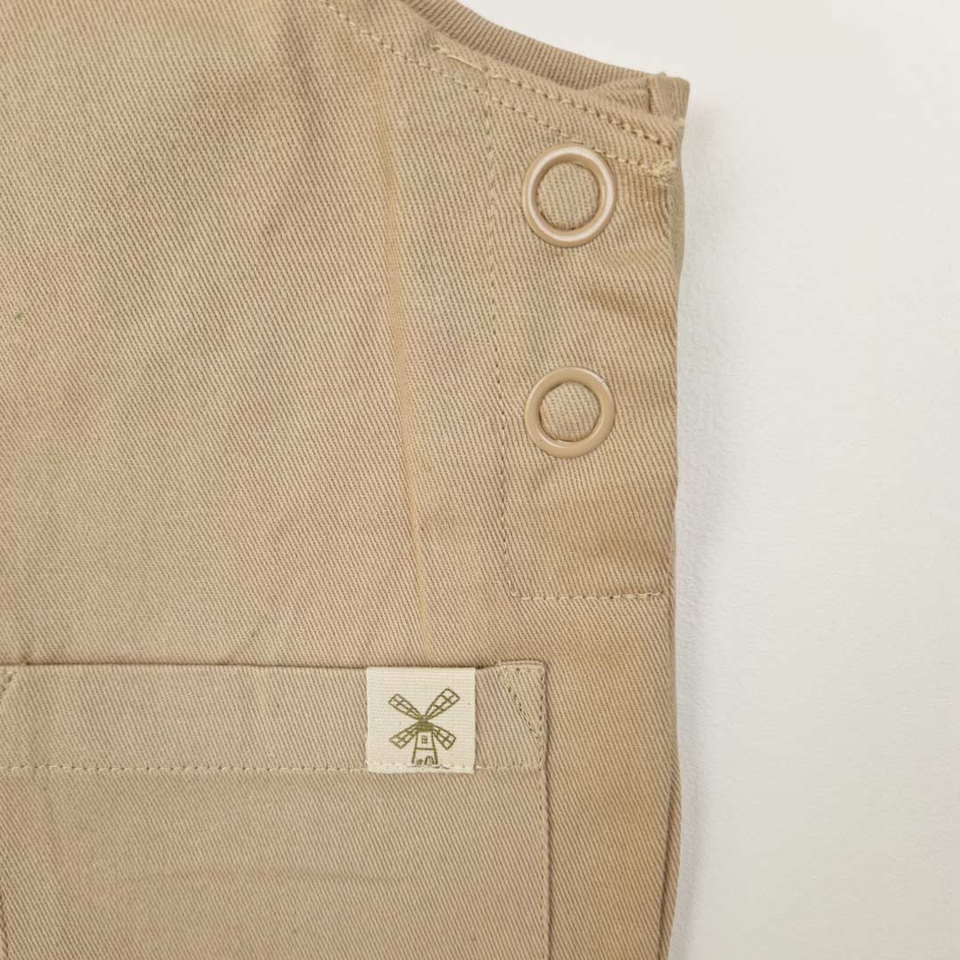 Front close up view of oat kids' dungarees with patch pockets, crafted from durable organic cotton. Close up image shows the details of the patch pocket with reinforced corner stitching and the Aneby windmill hemtag.