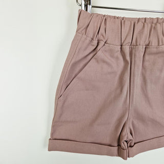 Dusty pink elasticated chino shorts hanging, back view with a close up of the detailed stitching, neutral background.