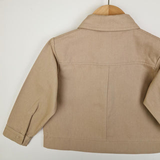 Back view of an oat-coloured kids' organic cotton shacket, featuring a timeless and minimalistic design.