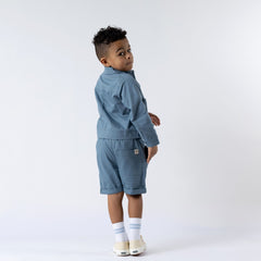 Back view of a slate blue kids' organic cotton shacket, showcasing the relaxed fit and durable stitching.