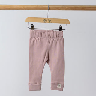A pair of dusty pink ribbed leggings hanging on a wooden frame. They are suspended from a wooden hanger that features the Aneby windmill logo. The elasticated waistband is slightly gathered.
