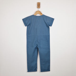 Back of slate blue short sleeve overall with patch pocket on right leg and rolled hem