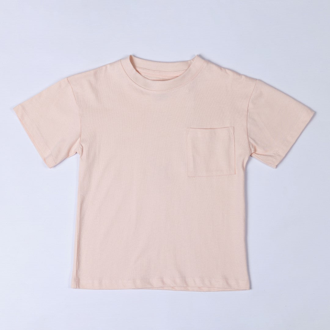 Flat lay of a blush pink kids t-shirt, showing the front design which features a pocket on the left side.