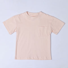 Flat lay of a blush pink kids t-shirt, showing the front design which features a pocket on the left side.