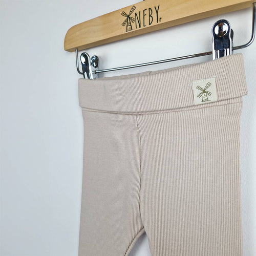 Close up view of organic oat ribbed baby leggings, showcasing the ribbed texture and high-quality stitch work on the waistband and the Aneby windmill hem tag on the waistband. The soft fabric is ideal for babies' sensitive skin.
