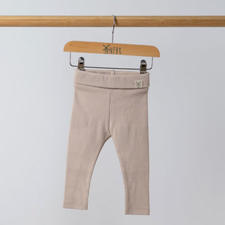 Organic oat ribbed baby leggings shown from the front, with the Aneby hem tag visible on the waistband. The soft ribbing and high-quality organic fabric are highlighted.