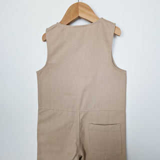 kids sleeveless overall in oat, back close up view, displayed against a neutral background.