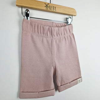 Front view opink ribbed organic cotton kids shorts hanging on a wooden hanger, with neutral background.