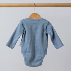 Back view of a slate blue ribbed bodysuit with long sleeves for babies, hung on a wooden hanger, showing soft ribbed fabric.