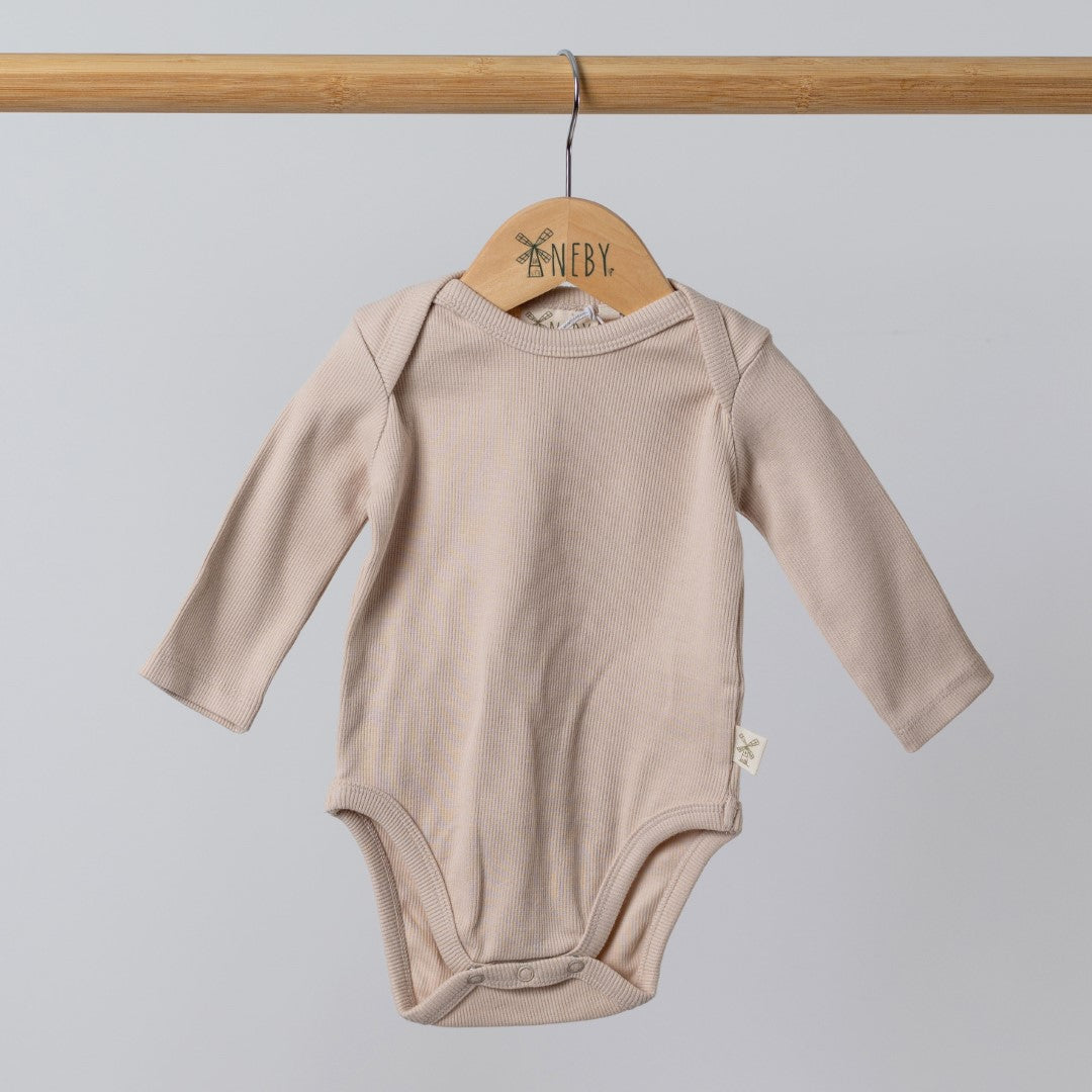 Oat-coloured ribbed bodysuit with long sleeves for babies, hanging on a wooden hanger against a plain background.