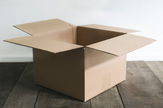 Cardboard box representing eco packaging sitting on rustic wooden floorboards