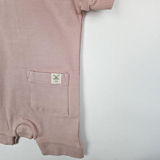 Dusty pink short sleeve rib baby romper close up image og back patch  pocket on right side with Aneby hem tag visible.